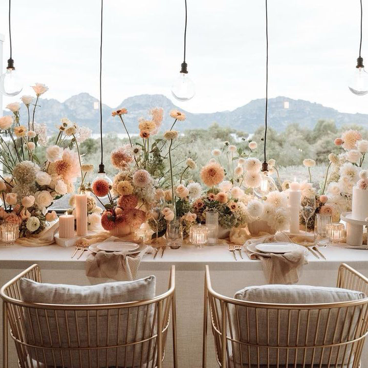 Beautiful photograph of a wedding table with stunning floral arrangements in muted neutral tones running down the length, the Hazard Mountains can be seen in the distance
