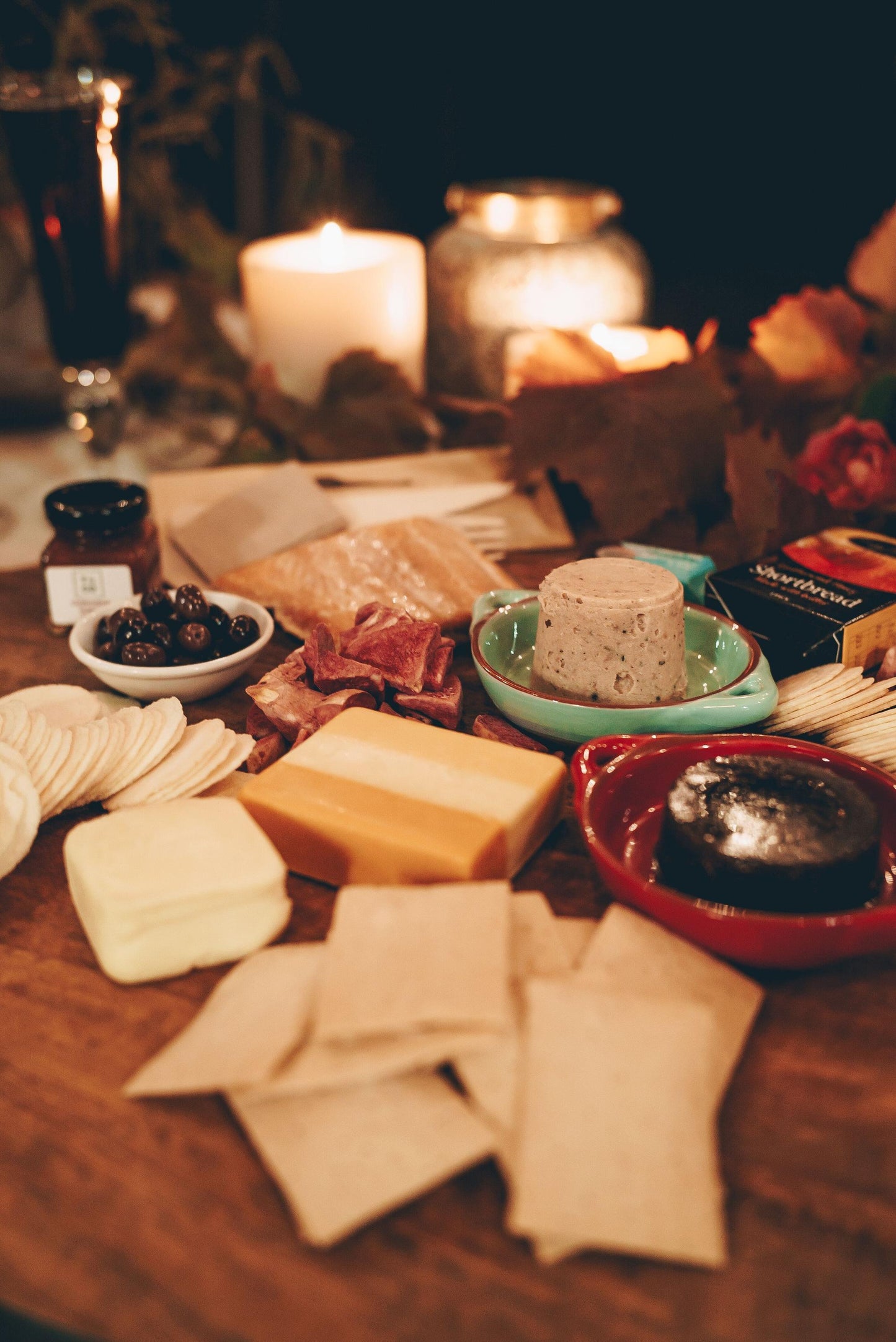 Photograph of platter containing Ashgrove cheese, salmon rillettes, lavosh, quince paste and other goodies, lit by candle light