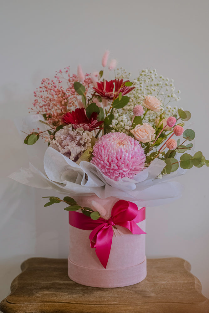 A pastel pink hatbox containing pink flowers