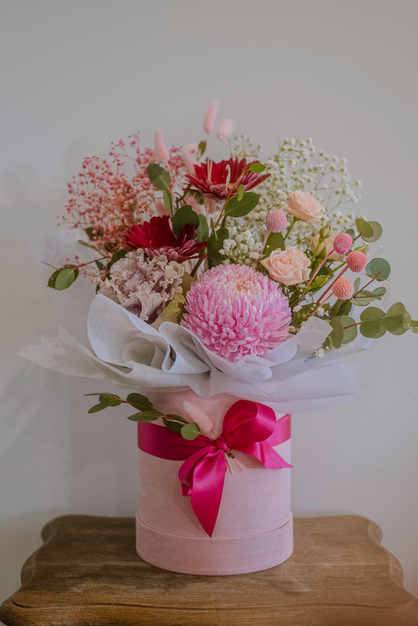 A pastel pink hatbox containing pink flowers
