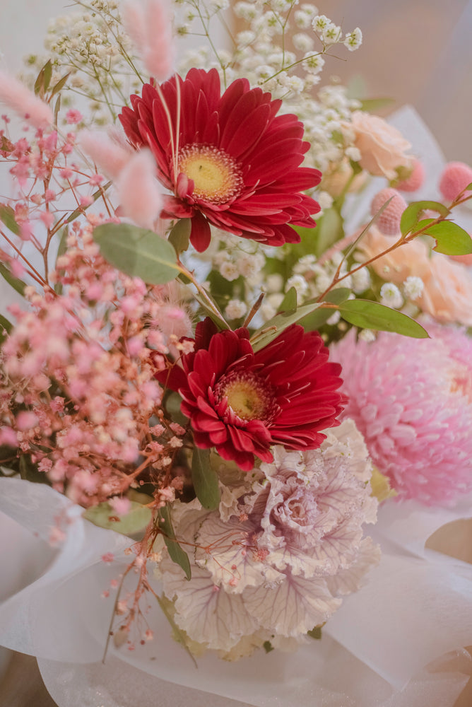 
                  
                    Close up of pink and red flowers in a pastel pink hatbox
                  
                