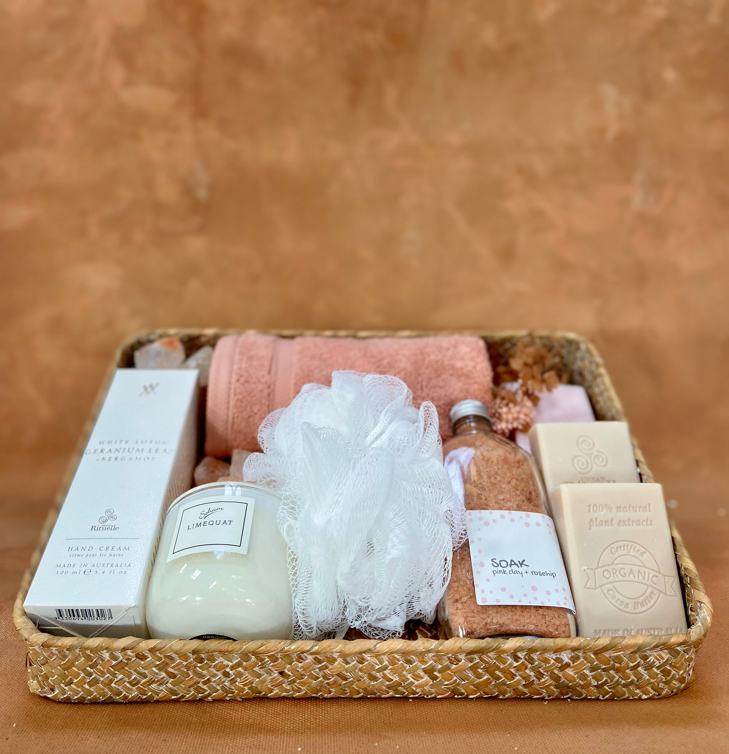 Photograph of a basked containing a beautiful floral baby muslin, luxe baby lotion and wash and a fluffy blue rabbit holding some dried flowers