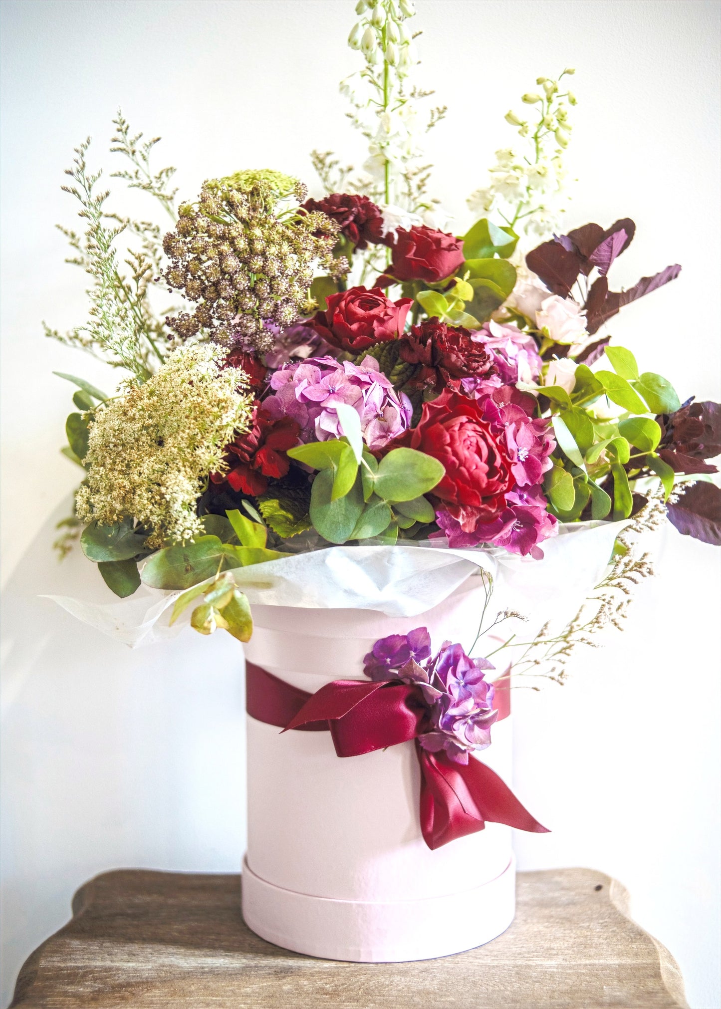 Photograph of a light pink hatbox with beautiful green and pink florals