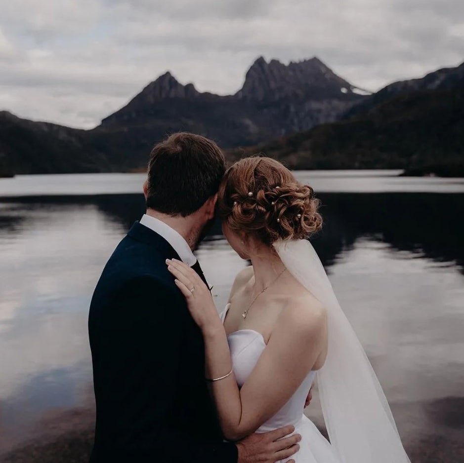 Photo of a wedding couple embracing with Cradle Mountain and Dove Lake in the distance