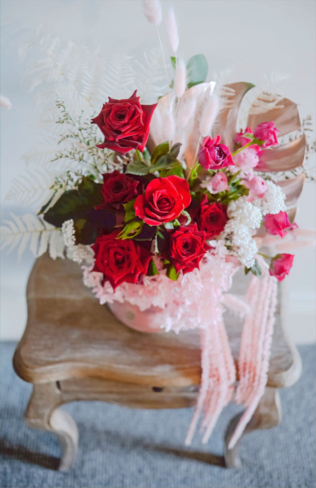 
                  
                    Red, pink and white roses and preserved florals in a ceramic pot
                  
                