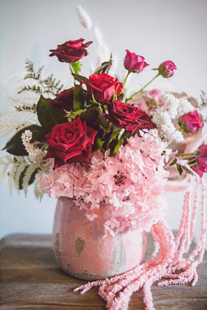 
                  
                    Red, pink and white roses and preserved florals in a ceramic pot
                  
                